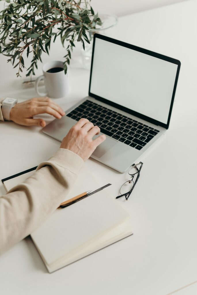 pexels-photo-4065864-4065864 A clean and modern workspace featuring a laptop, houseplant, and notebook.